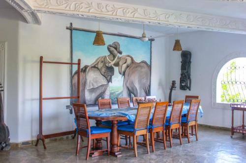 a dining room with a painting of elephants on the wall at Sal & Lala villa watamu in Watamu