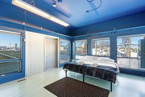 a bedroom with a bed with blue walls and windows at Tranquil 3-Bedroom Home in Prince George in Prince George