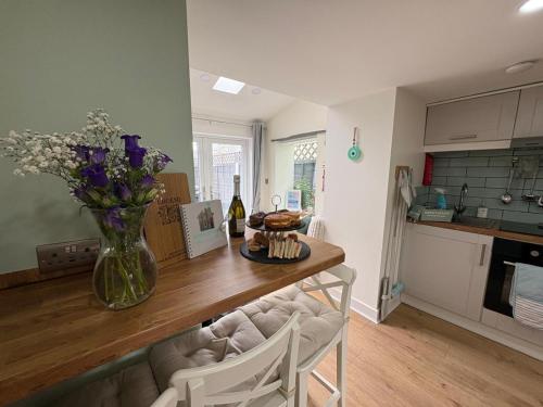 a kitchen with a table with a vase of flowers at Gwens House - Traditional Cottage With Hot Tub in Brynsiencyn
