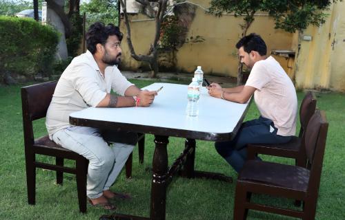 two men sitting at a table in the grass at Amrit resort in Alwar