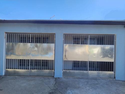 two metal garage doors with windows on a white building at Um lugar para recordar in São José dos Campos