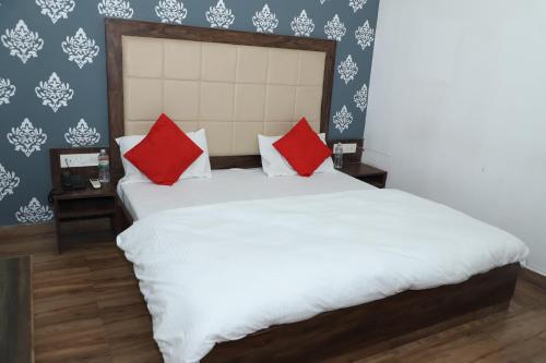 a bedroom with a large white bed with red pillows at Amrit resort in Alwar