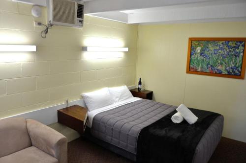 a bedroom with a bed and a couch and a chair at Charles Sturt Motor Inn in West Wyalong