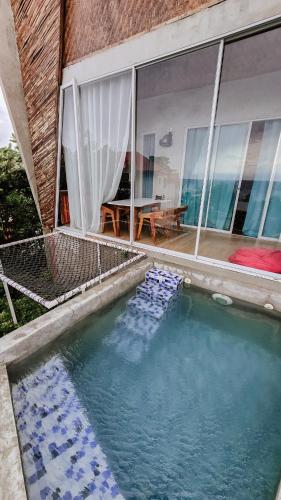a swimming pool in front of a house with windows at The Verge Cebu Beachfront King Bed Pool Villa - 12 Minutes to Kawasan Falls Canyoneering in Badian
