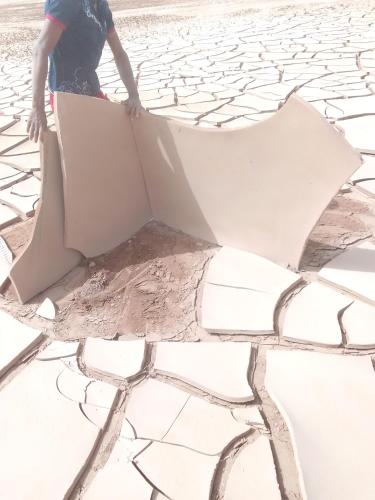 a man standing on a cracked ground with a piece of paper at désert tours & Hôtel Titanic lac irik in Foum Zguid