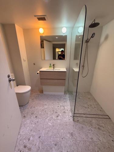 a bathroom with a sink and a toilet and a mirror at Grande Esplanade Studio - New bathroom in Sydney