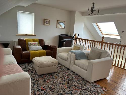 a living room with couches and chairs and a staircase at Breathtaking view in Carrigart