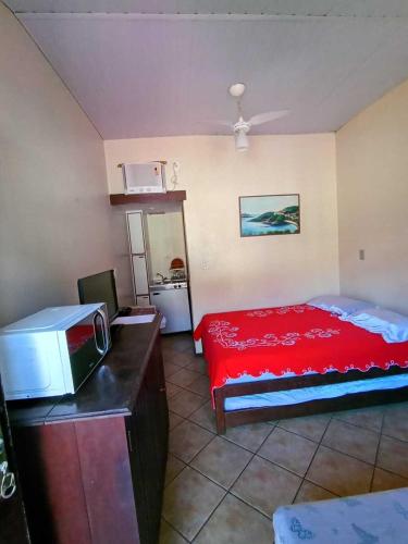 a bedroom with a red bed and a microwave at Aparthotel Praia do Pero in Cabo Frio