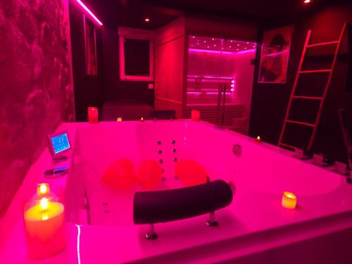 a pink bath tub with a chair in a room at La Cachette Secrete - Love Room à Caen en Normandie avec Balnéo et Sauna Privatif in Caen