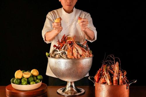 a chef is standing next to a bowl of food at Renaissance Kuala Lumpur Hotel & Convention Centre in Kuala Lumpur