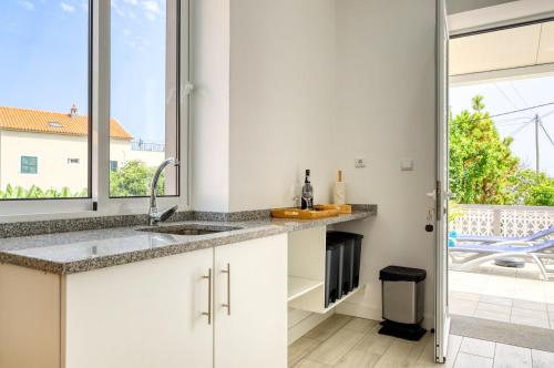 kuchnia z białymi szafkami i dużym oknem w obiekcie Casa da Tia Celeste I, a Home in Madeira w mieście Ponta do Sol