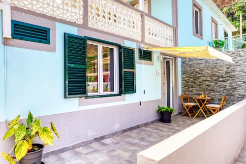 a patio of a house with a table and a yellow umbrella at Casa da Tia Celeste III, a Home in Madeira in Ponta do Sol
