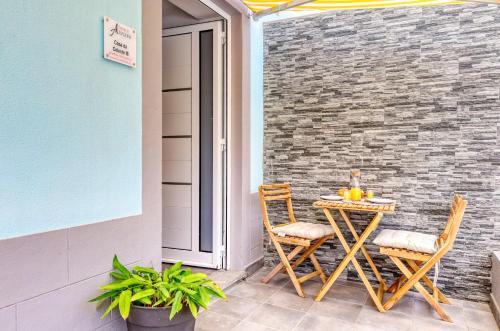 a table and chairs on a patio with a brick wall at Casa da Tia Celeste III, a Home in Madeira in Ponta do Sol