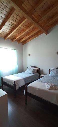 two beds in a room with wooden ceilings at Casa de campo a 5 minutos da praia in Atouguio