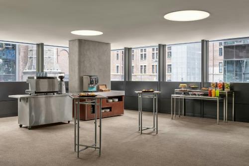 a kitchen with tables and stools in a room with windows at Four Points by Sheraton Sydney, Central Park in Sydney