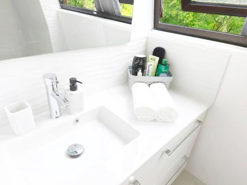 a white bathroom with a sink and a window at Coulounieix Resort in Coulounieix-Chamiers