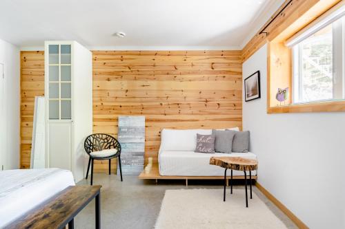 a bedroom with wooden walls and a bed and a window at Hummingbird Room - Modern & Cozy with Bistro Area in Mansonville
