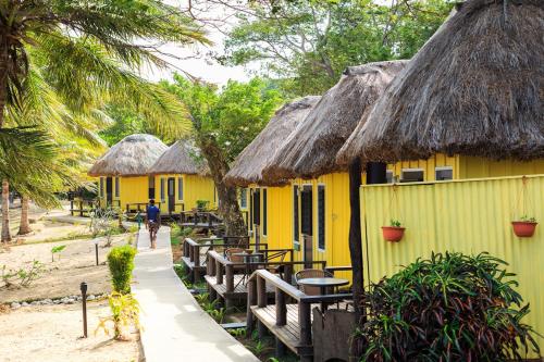 a row of yellow houses with thatched roofs at Funky Fish Beach & Surf Resort in Malolo