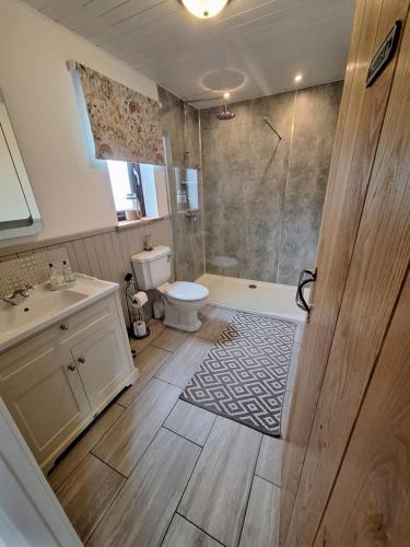 a bathroom with a shower and a toilet and a sink at Riverside in Skeabost