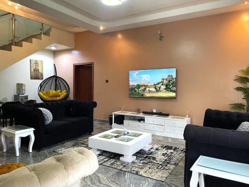 Una televisión o centro de entretenimiento en Luxury 4 BR Apt w Parking, Hot tub, Magodo Estate