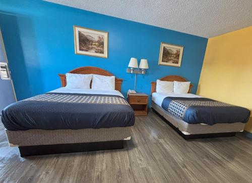 two beds in a hotel room with blue walls at western skies motel in Clarendon