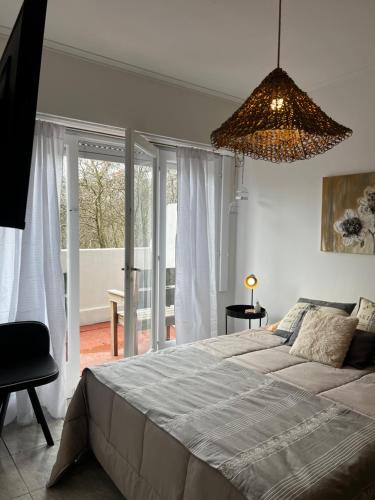 een slaapkamer met een groot bed en een kroonluchter bij Alfonsina Departamento cerca del mar in Mar del Plata