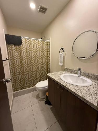 a bathroom with a sink and a toilet and a mirror at Tropical Sunshine in Alajuela