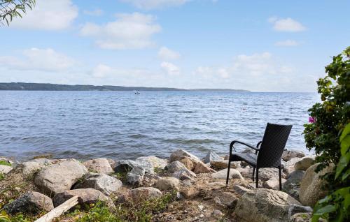 a chair sitting on the rocks by the water at Awesome Home In Børkop With Wifi in Børkop