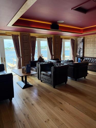 a living room with couches and a table and windows at Andreas Riverside Retreat at 7 Lakes Country Park in Crowle