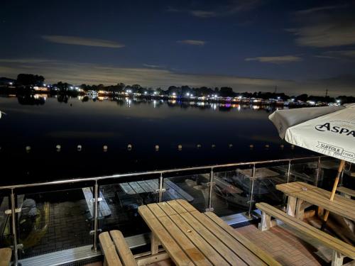 a dock with a bench and an umbrella on a boat at Andreas Riverside Retreat at 7 Lakes Country Park in Crowle