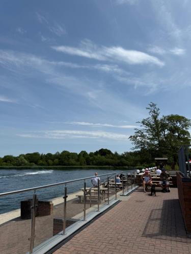 a group of people sitting on a pier next to a river at Andreas Riverside Retreat at 7 Lakes Country Park in Crowle