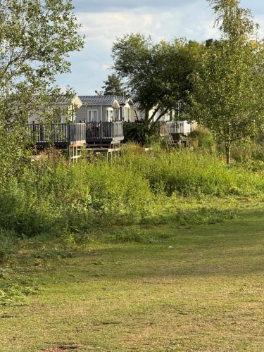 a field of grass with a house in the background at Andreas Riverside Retreat at 7 Lakes Country Park in Crowle