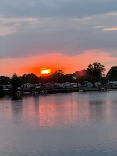 a sunset over a lake with the sun setting at Andreas Riverside Retreat at 7 Lakes Country Park in Crowle