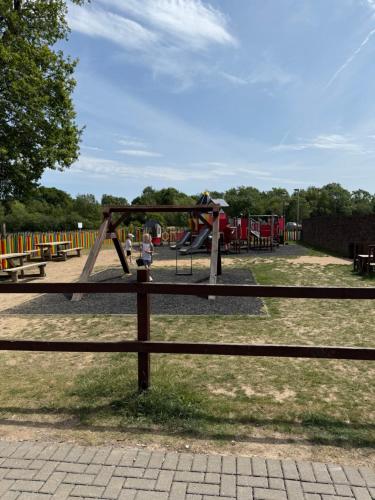 a wooden fence in a park with a playground at Andreas Riverside Retreat at 7 Lakes Country Park in Crowle