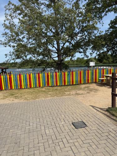a colorful fence with a tree in a park at Andreas Riverside Retreat at 7 Lakes Country Park in Crowle