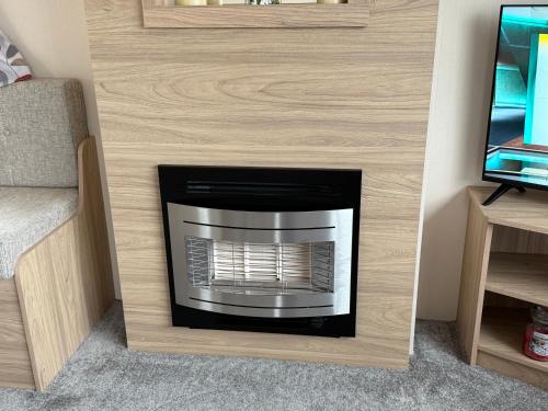 a fireplace in a living room with a tv at Andreas Riverside Retreat at 7 Lakes Country Park in Crowle