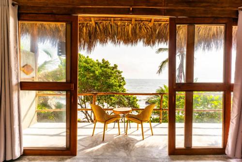 a patio with a table and chairs and the ocean at Finca Barlovento Maloka, Tayrona Park in Los Naranjos