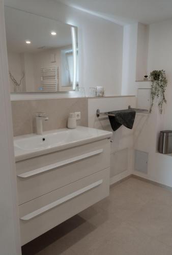 a white bathroom with a sink and a mirror at Ferienwohnung Traumblick in Bretzfeld