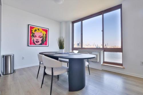 a dining room with a table and chairs and a large window at Hudson River waterfront apt w sweeping NYC views in Hoboken
