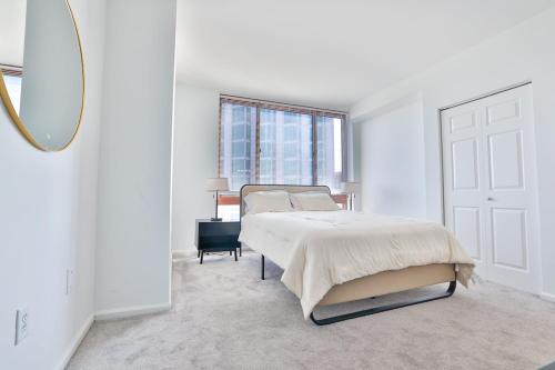a white bedroom with a bed and a mirror at Hudson River waterfront apt w sweeping NYC views in Hoboken