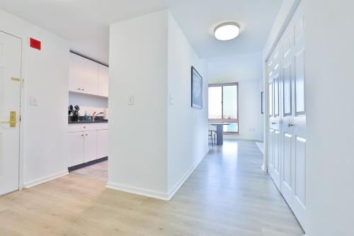 an open kitchen with white walls and wooden floors at Hudson River waterfront apt w sweeping NYC views in Hoboken