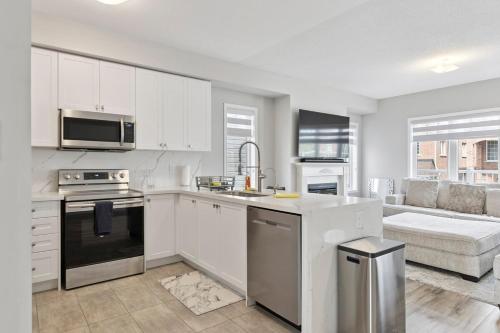 a kitchen with white cabinets and a stove top oven at The Devineridge Executive House in Ajax