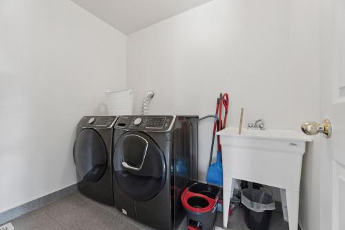 a laundry room with a washing machine and a sink at The Devineridge Executive House in Ajax