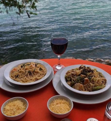 a table with two plates of pasta and a glass of wine at El Encantadero in Jobompiche