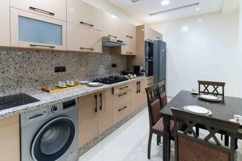 a kitchen with a washing machine and a table with chairs at Appart Hôtel Golden Sky Home Café Restaurant & Spa in Beni Mellal