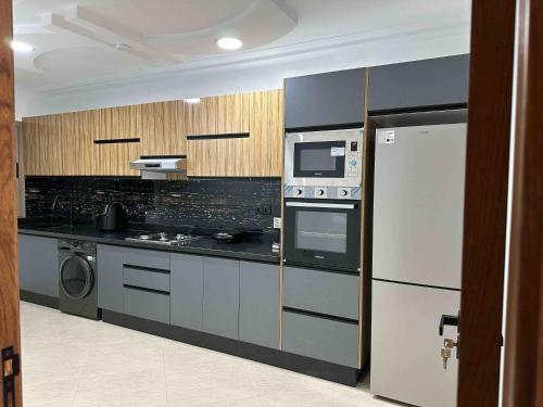 a kitchen with a refrigerator and a stove and a microwave at Appart Hôtel Golden Sky Home Café Restaurant & Spa in Beni Mellal