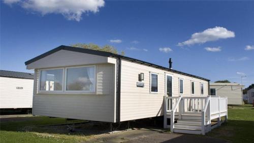 a small white trailer with a porch and a house at Beech Rise, Primrose Valley, Filey in Filey