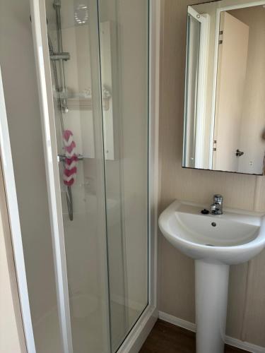 Un baño con lavabo y ducha de cristal. en Beech Rise, Primrose Valley, Filey, en Filey