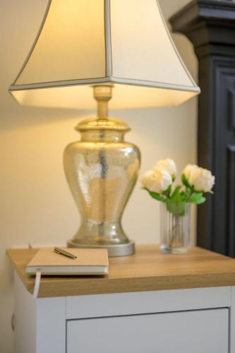 a lamp on a table with a notebook and flowers at Escape to Serene Georgian Estate, near Edinburgh in Ratho