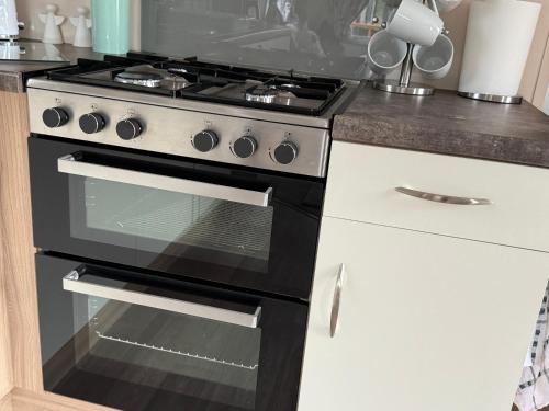 a kitchen with a black stove and white cabinets at Andreas Riverside Retreat at 7 Lakes Country Park in Crowle